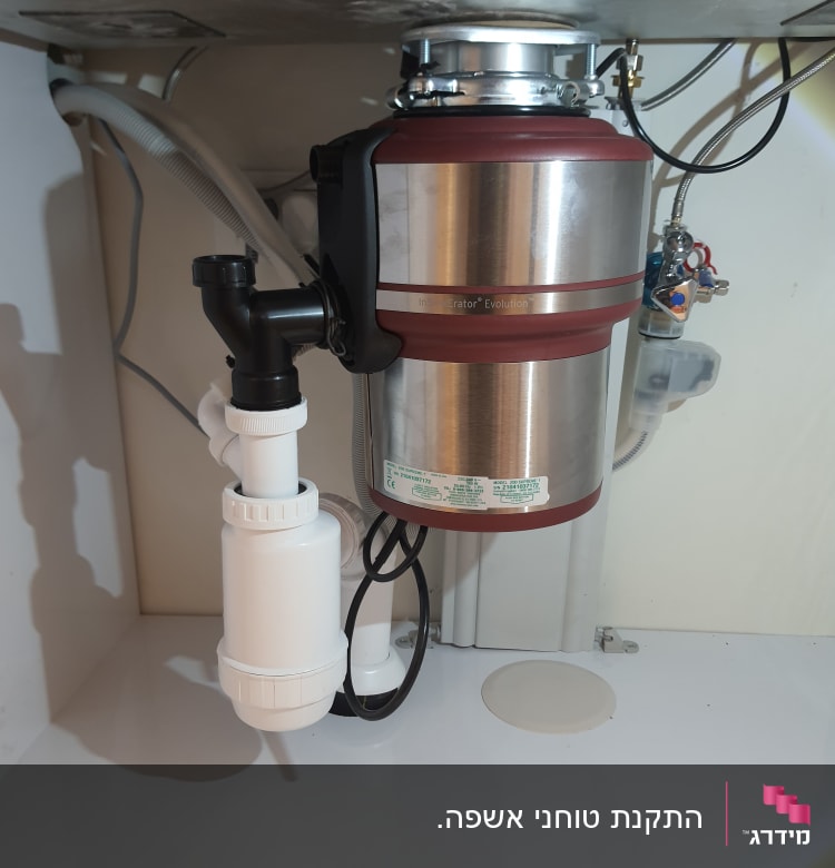 מכשיר טוחן אשפה מתחת לכיור עם צינורות חיבור